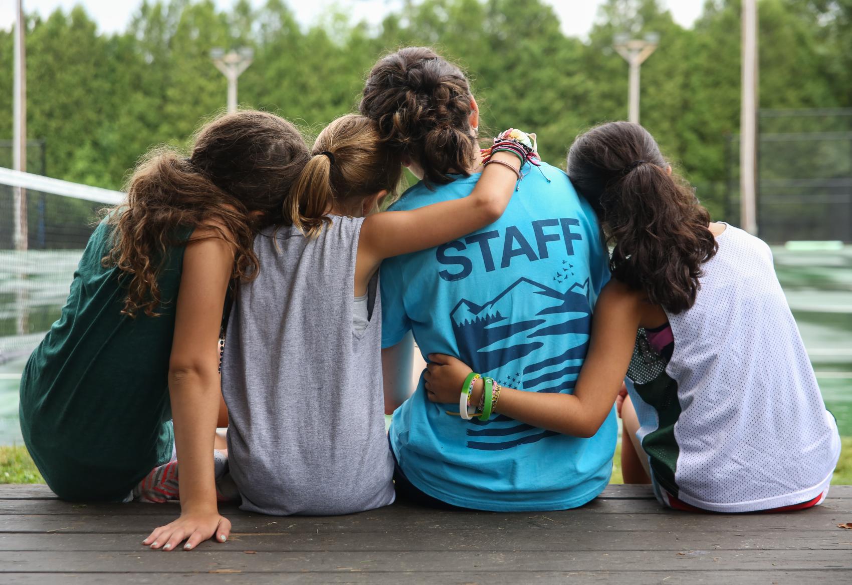 campers with their arms around a camp staff member