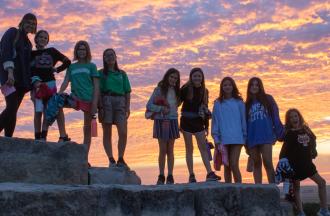 camp group in front of sunset