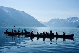 Campers in canoes on lake with mountains in background