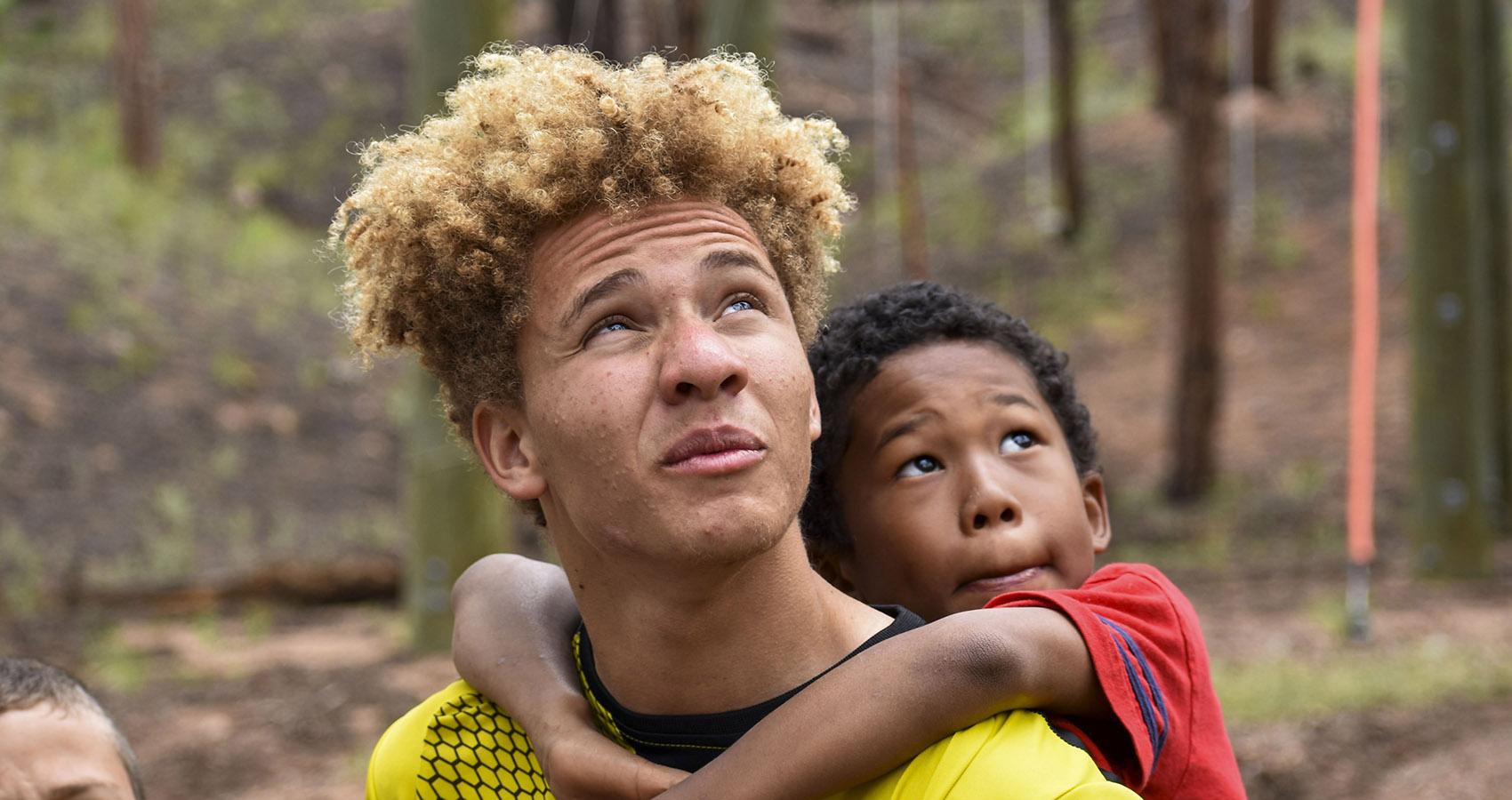 camper hanging on to counselor's shoulders