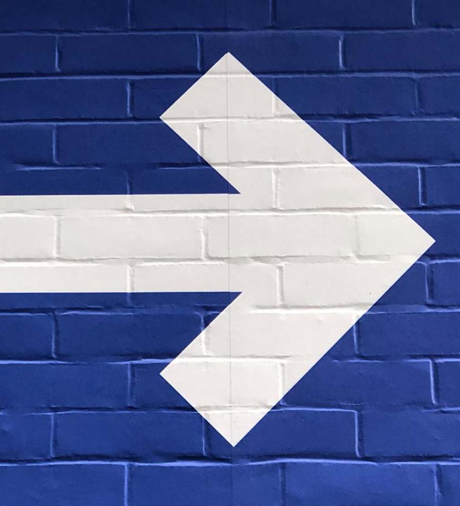 white arrow painted on blue wall