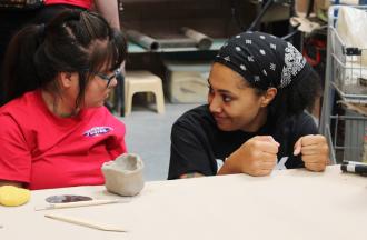 camper and staff doing pottery