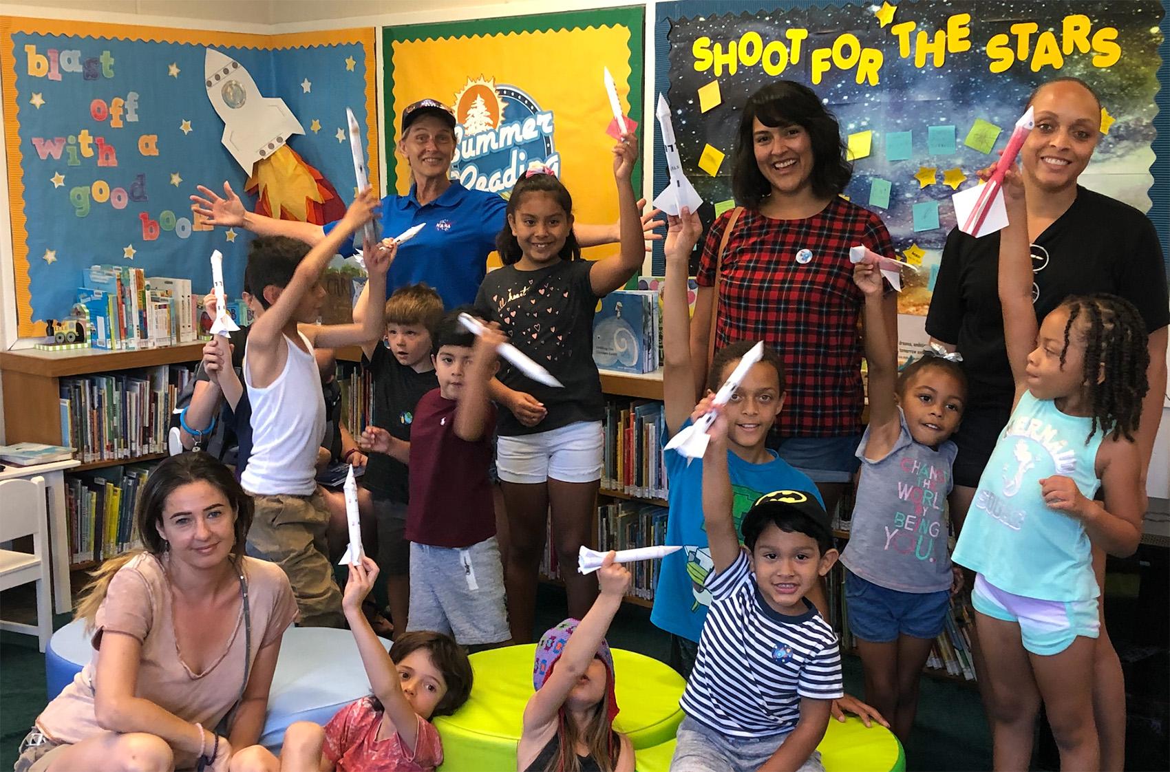 kids with teachers holding paper rockets