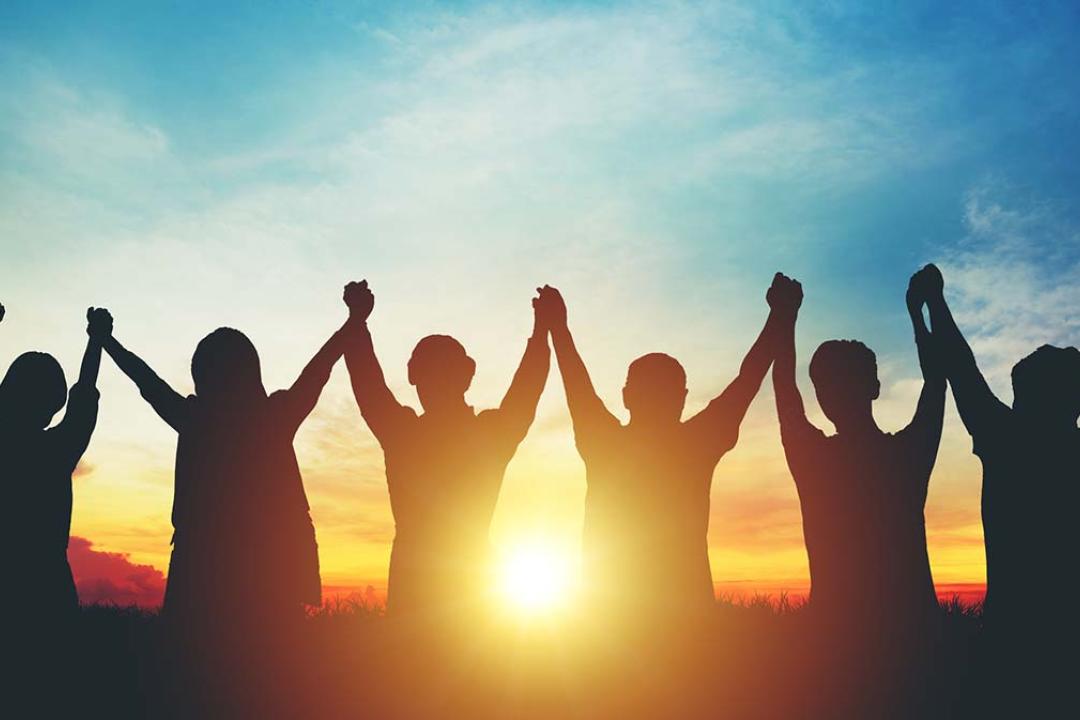 stock photo of people holding hands at sunset