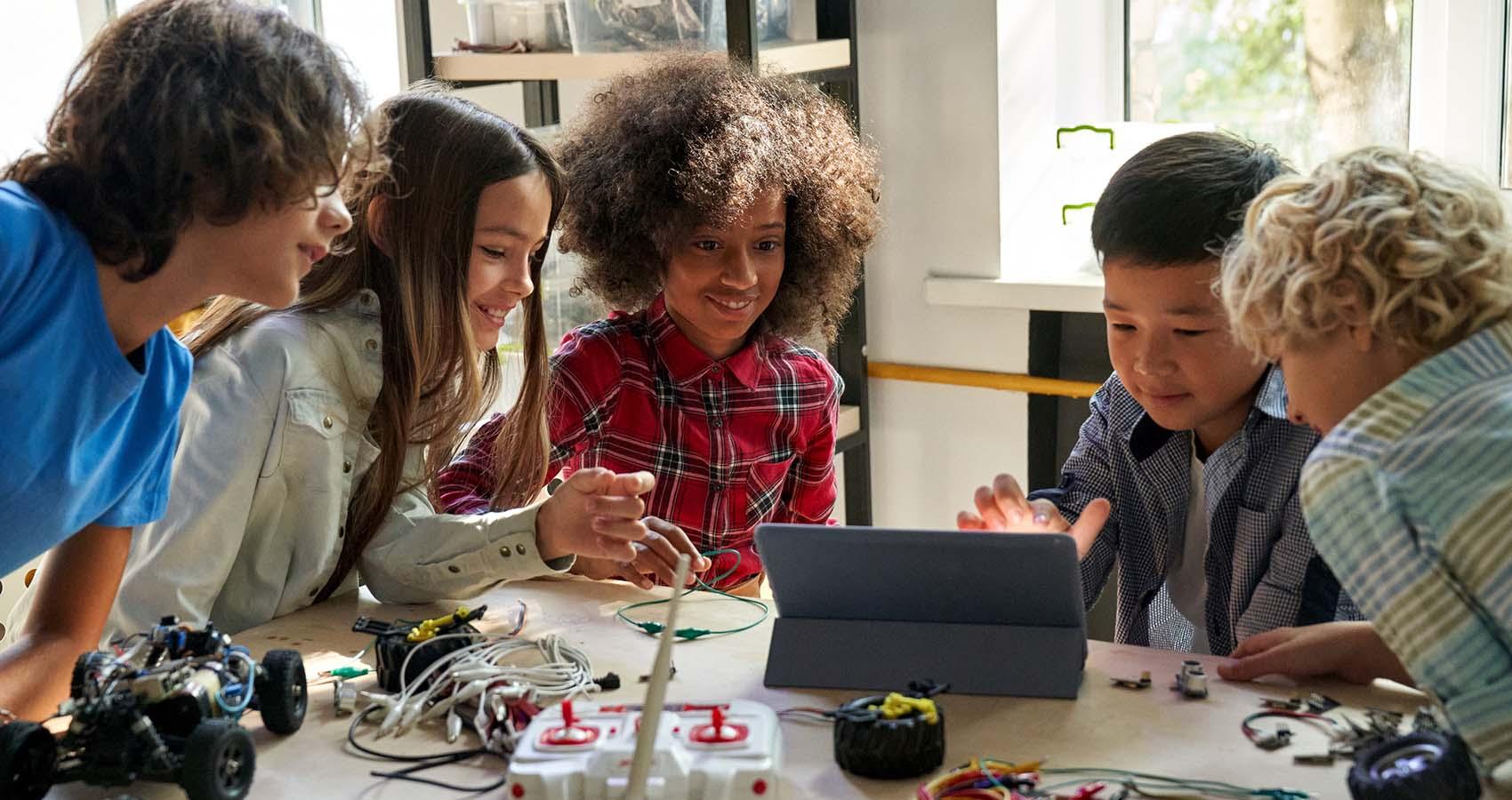 Young student working on remote-controlled car and tablet