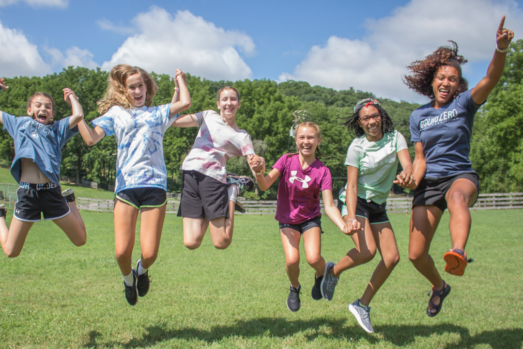 Counselor and campers jumping into the air